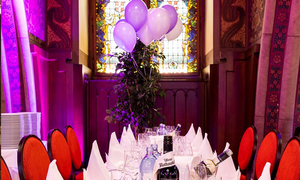 Gedeckter Geburtstagstisch im Rittersaal, violette Luftballons im Hintergrund
