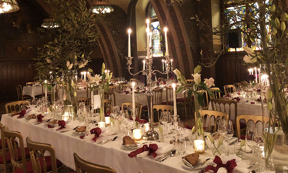 weiß gedeckte lange Tafeln im Rittersaal, dekoriert mit Blumengestecken, Kerzenleuchtern und Rosenblättern anlässlich einer Hochzeit