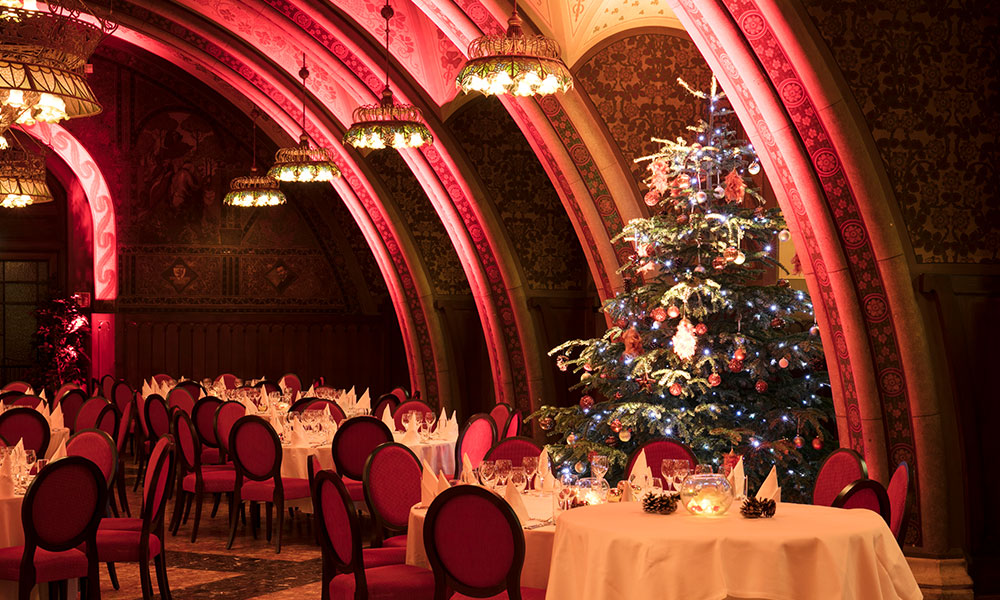 Weihnachtsfeier im historischen Rittersaal mit festlich gedeckten Tischen und einem geschmückten Christbaum im Hintergrund