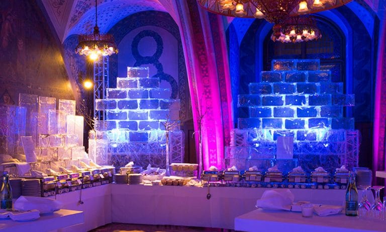 Blau und violett beleuchteter Veranstaltungssaal mit Eisblöcken dekoriert und einem aufgebauten Buffet